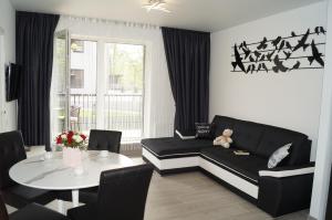 een woonkamer met een zwarte bank en een tafel bij Apartamentai Vyta Plius in Klaipėda