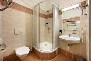 a bathroom with a shower and a toilet and a sink at Hotel Golden City Garni in Prague