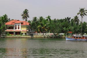 a house and a boat on a river with a house at Water's Edge Villas in Alleppey
