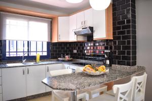a kitchen with white cabinets and a granite counter top at TC Tríplex Bahía Meloneras in Meloneras
