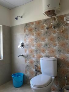 a bathroom with a toilet and flowers on the wall at Heschuk Guest House in Leh