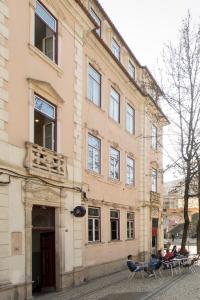 a building with people sitting on chairs in front of it at Solar da República in Coimbra