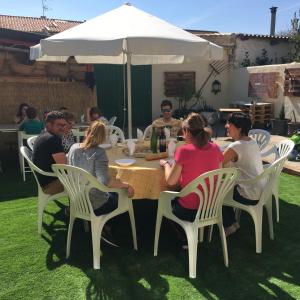 a group of people sitting around a table under an umbrella at La Manguita Bardenas in Arguedas