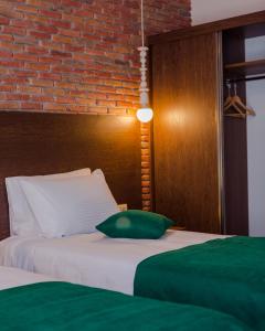 a bed with a green pillow and a brick wall at HOTEL BLOOM in Batumi