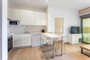a kitchen with white cabinets and a table and chairs at ApartUP Patacona Beach Select in Valencia