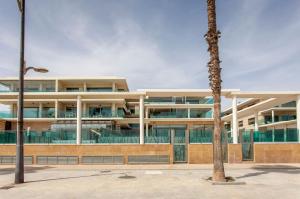 a building with a palm tree in front of it at ApartUP Patacona Beach Select in Valencia