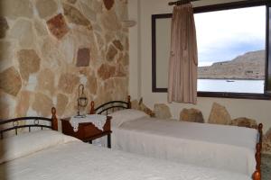 two beds in a room with a stone wall at Athena Rooms in Kato Zakros