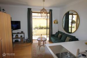 a living room with a green couch and a mirror at StellaHome - La petite cour in Sanary-sur-Mer