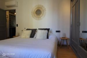 Schlafzimmer mit einem weißen Bett und einem Spiegel an der Wand in der Unterkunft StellaHome - La petite cour in Sanary-sur-Mer