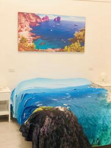 una camera da letto con un dipinto dell'oceano sul muro di Penisola Home Experience a Vico Equense