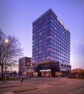 a large glass building in front of a parking lot at Olympic Hotel in Amsterdam