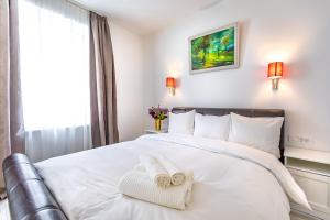 a bedroom with a white bed with a towel on it at Casa Atanasiu lângă Biserica Neagră în Centrul Istoric in Braşov +25 photos