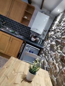 cocina con mesa y pared de piedra en Cwm Farm Cwtch, en Merthyr Tydfil
