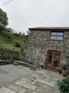 una casa in pietra con una porta di legno di fronte di Cwm Farm Cwtch a Merthyr Tydfil