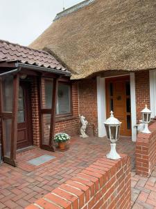 a brick house with a thatch roof and a brick patio at Ferienwohnung Anna Frieda in Loxstedt