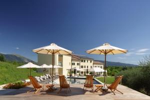un gruppo di sedie e ombrelloni accanto alla piscina di Colonìa Resort a Vittorio Veneto