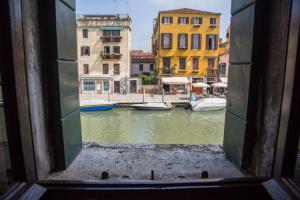 a view from a window of a canal with boats at La Colombina in Venice
