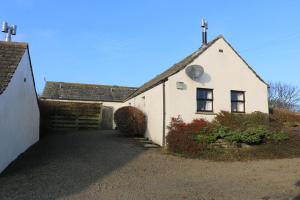 a white building with a cross on the top of it at Eviedale Cottages in Evie