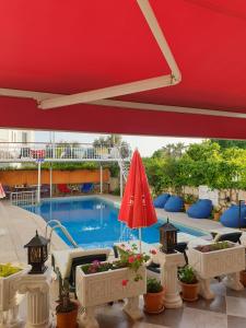 a red umbrella and some plants and a swimming pool at Dalyan Tulip Apart Hotel in Dalyan