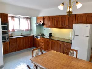 een keuken met houten kasten, een tafel en een koelkast bij Departamento Costanera in Bariloche