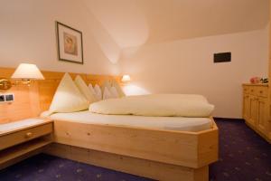 a bedroom with a wooden bed with a nightstand and a bed sidx sidx sidx at Haus Niederweg in Tirolo