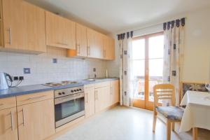 cocina con armarios de madera, mesa y ventana en Haus Niederweg, en Tirolo