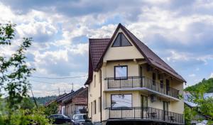 a house with a balcony and cars parked in front of it at Casa Sky in Orşova
