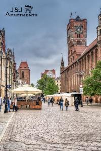 grupa ludzi chodzących po ulicy z wieżą zegarową w obiekcie J&J Apartments Szeroka 25 Apartament 1 w Toruniu