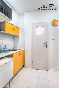 kuchnia z pomarańczowymi i białymi szafkami oraz drzwiami w obiekcie J&J Apartments Szeroka 25 Apartament 1 w Toruniu