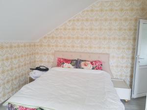 a bedroom with a white bed with floral wallpaper at Casa Cojanu in Petroşani