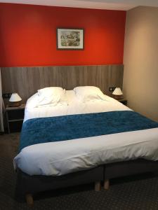 a bedroom with a large bed with a red wall at Hôtel Les Frangins in Saint-Omer