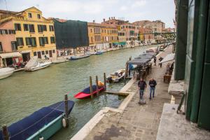 a couple of people walking down a canal with boats at La Colombina in Venice