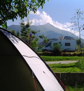 a tent and a trailer with a mountain in the background at CAMPING IL MELO in Peveragno
