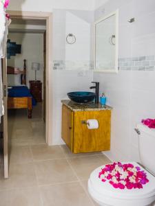 een badkamer met een wastafel en een toilet met bloemen op de vloer bij Calliandras Apartment Complex in Kingstown