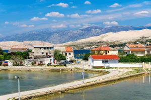 a town next to a river with mountains in the background at Apartments Rija in Pag