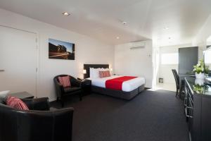 een hotelkamer met een bed, een bureau en stoelen bij The Dawson Motel in New Plymouth