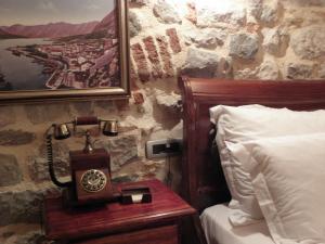 a bed sitting next to a wall next to a lamp at Hotel Villa Duomo in Kotor