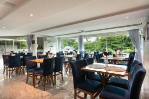 a restaurant with wooden tables and chairs and large windows at Nord Luxxor Cabo Branco in João Pessoa