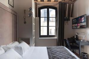 a bedroom with a bed and a window and a desk at Hôtel Le Presbytère in Paris