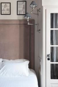 a bedroom with a white bed with a brown headboard at Hôtel Le Presbytère in Paris