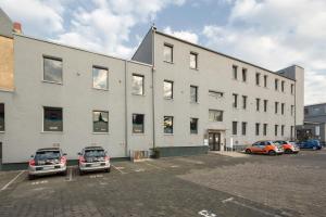 un gran edificio blanco con coches aparcados en un aparcamiento en T3 Hotel Cityloft, en Mönchengladbach