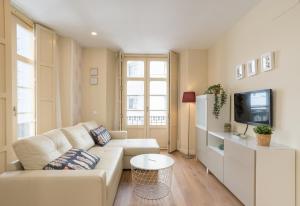 ein Wohnzimmer mit einem weißen Sofa und einem TV in der Unterkunft LU&CIA SOHO 2 in Málaga