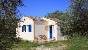 een klein wit huis met blauwe deuren en een tafel bij Pamar Village in Lefkada