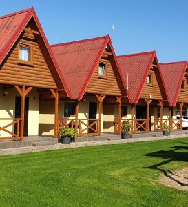 budynek z czerwonymi dachami i zieloną trawą w obiekcie Domki letniskowe Kika w Sarbinowie