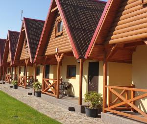 a row of cottages with wooden roofs at Domki letniskowe Kika in Sarbinowo