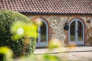a brick house with two windows and a roof at The Old Stables in Docking
