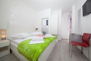 a white bedroom with a green bed and a red chair at Villa Matić in Makarska +37 photos