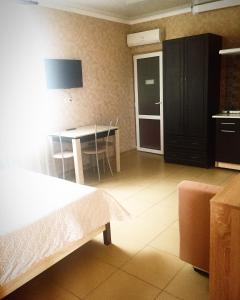 Zimmer mit einem Bett und einem Tisch sowie einer Küche in der Unterkunft Guest house on Kamyshovaya 12 a in Adler