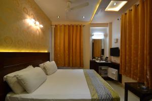 a bedroom with a bed and a desk and a television at Hotel Central Residency in Varanasi