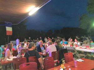 un gran grupo de personas sentadas en las mesas por la noche en Village Vacances Yaloer, en Villefranche-de-Panat